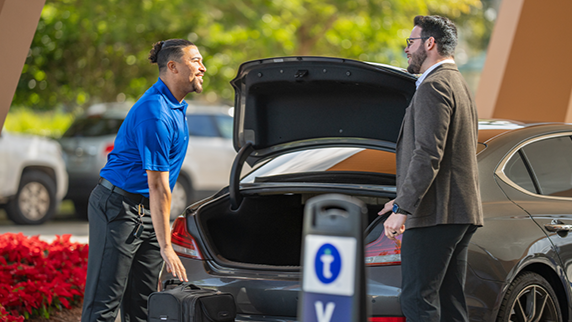 Towne valet associate greeting a hotel guest at vehicle arrival, representing the people-first service philosophy behind Towne's Power of WOW